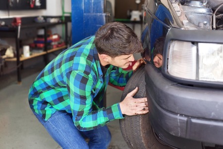 Mecanic checking car suspension system, at repair service station.の写真素材