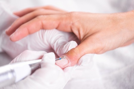 Professional manicure process, cleaning the nails with a manicure milling cutter, at beutician salon.の写真素材