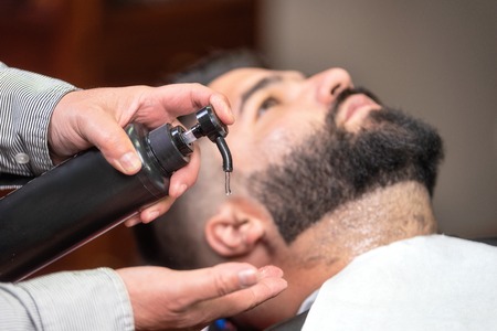 Hair stylist applying after shaving lotion at barber shop.の写真素材