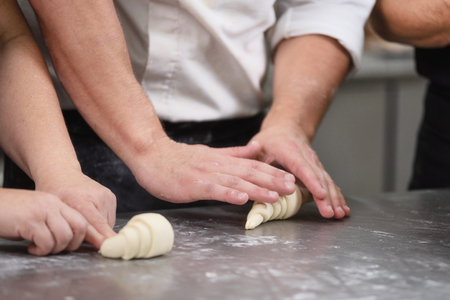 Pastry Chef rolling fresh raw croissant dough.の写真素材
