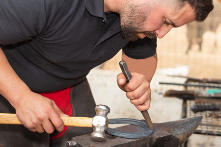 Blacksmith working on the anvil, making a horseshoe.の写真素材