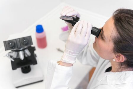 Doctor examining urine in laboratory, with refractometer, closeup.