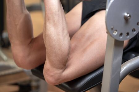Man flexing isquiotiobial leg muscles on leg curl gym machine. Sport, fitness, bodybuilding and...
