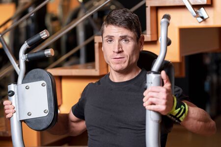 Handsome muscular man working out hard at gym. Training Chest exercises. Chest workouts.