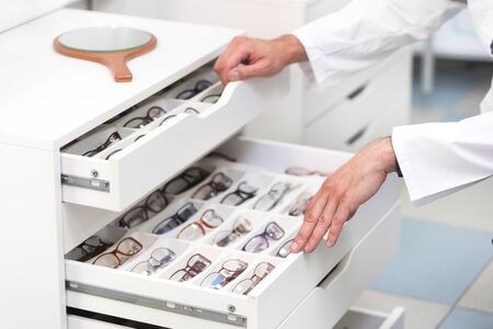 ophthalmologist hands close up, choosing glasses from a drawer in the optical store.の写真素材