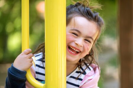 Cute girl enjoying on playground in the park in summertime.
