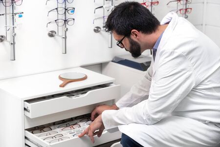 ophthalmologist choosing glasses from a drawer in the optical store.