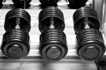 Different sizes and weights of dumbbell free weights at a gym in black and white.の写真素材