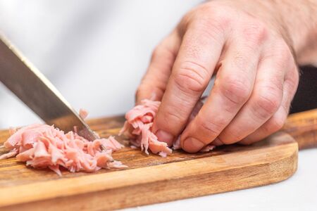 Chef slicing ham on wooden table.の写真素材