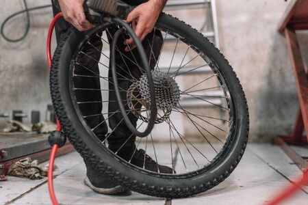 Mechanic repairing a bicycle tire flat in a small workshop.の写真素材
