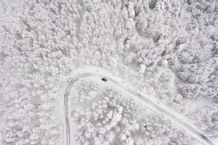 Car on road in winter trough a forest covered with snow. Aerial photography of a road in wintertime trough a forest covered in snow. High mountain pass.の写真素材