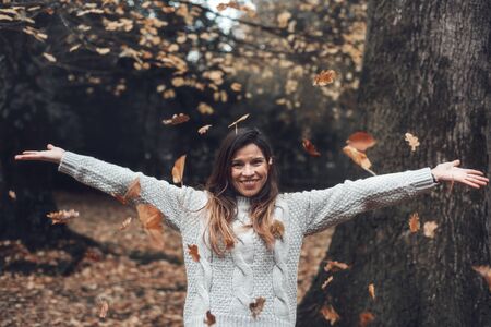Portrait of a woman in the autumn park, throwing up fallen leaves. Toned image.の写真素材