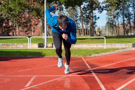 Young Man Starting sprint on Running Track .