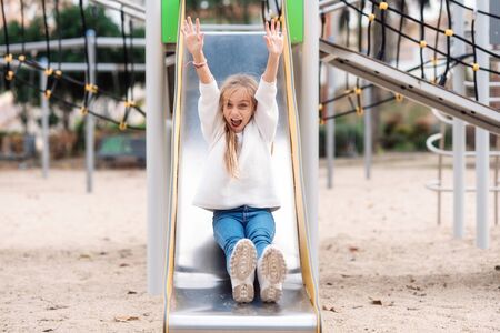 Happy little girl having fun on slide in park.の写真素材