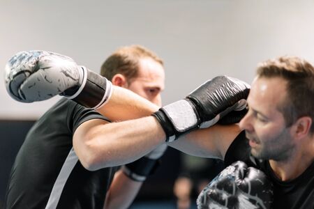 young man fighter, training kick boxing with his trainer, fighting in the ring.の写真素材