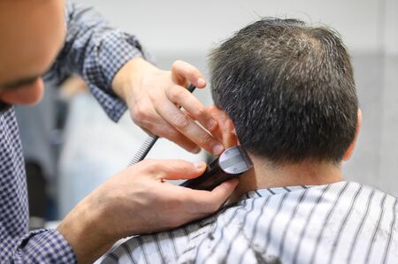 Barber trimming hair of old man at barber shop .の写真素材