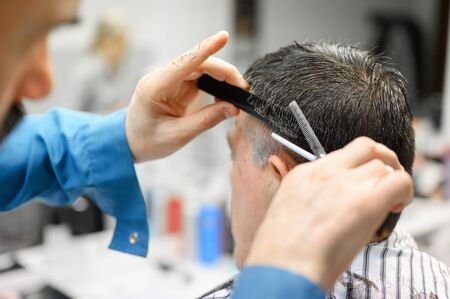 Barber trimming hair of old man at barber shop.の写真素材