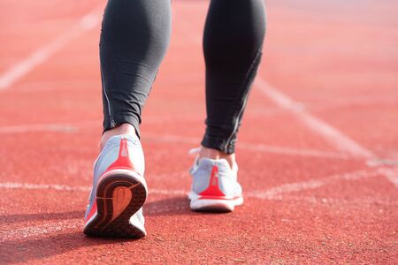 Athletic person on running track getting ready to start run, back view .