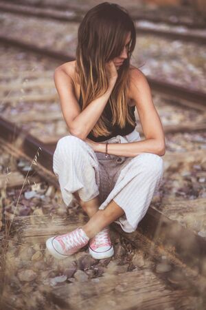 Sad young woman sitting on the railway.の写真素材