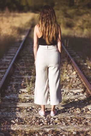 Old fashioned style photography. Back view, of of a woman standing on train tracks. concept of Choice or memories.の写真素材