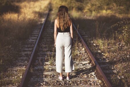 Old fashioned style photography. Back view, of of a woman standing on train tracks. concept of Choice or memories.の写真素材