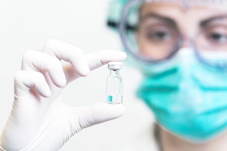 Doctor or nurse in protective gloves holding vaccine vial for Coronavirus outbreak pandemic....