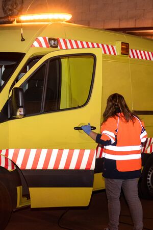 Night scene of an unrecognizable Paramedic, Ambulance woman driver at work, ready to assist an emergency .の写真素材