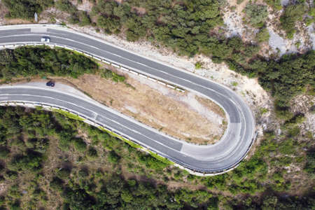 Aerial view of winding road in high mountain pass trough green pine woods. High quality photo