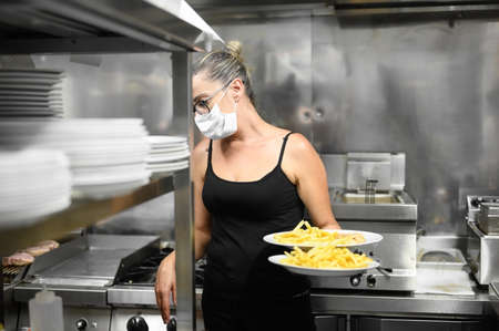 Young waitress with face protective mask working in restaurant. Coronavirus or Covid-19 concept.