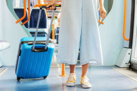 Close up of an unrecognizable woman carrying a suitcase, traveling by train.の写真素材
