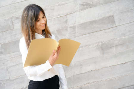 Business Woman smiling, holding documents in her hands.