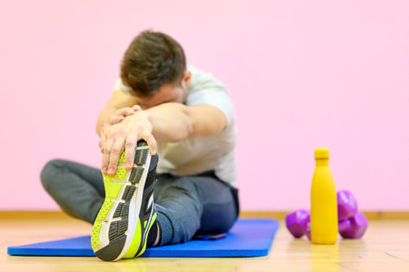 Portrait of a fitness man doing stretching exercises at gymの写真素材