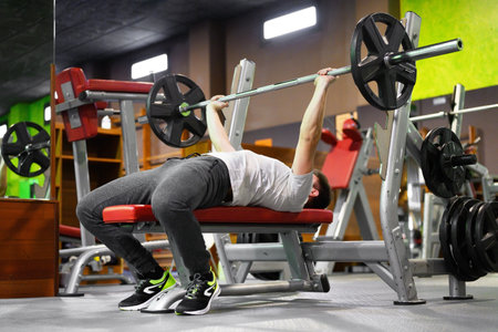 Young Man Doing Bench Press Workout In Gym