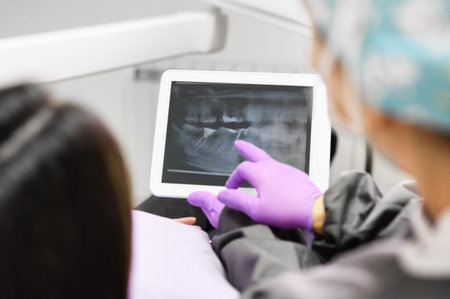 Health care concept - Female dentist showing tablet computer to woman patient at dental clinic office.の写真素材