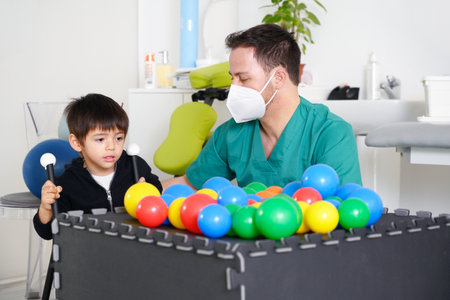 Child with cerebral palsy on physiotherapy in a children therapy center. Boy with disability doing exercises with physiotherapists in rehabitation centre.の写真素材
