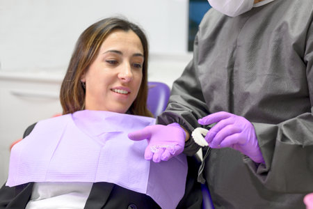 Dentist showing to woman patient an orthodontic silicone trainer. Mobile orthodontic appliance for...