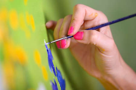 Close-up Shot of Female Artist Hand, Holding Paint Brush and Drawing Oil Painting. Contemporary...