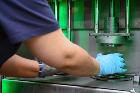 Steel Manufacturing Plant. A Worker is Placing a Piece of Metal Inside the Press. The Press is...