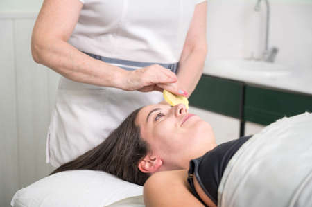 A beautician performs make-up removal from the clients face in a beauty salon.の写真素材