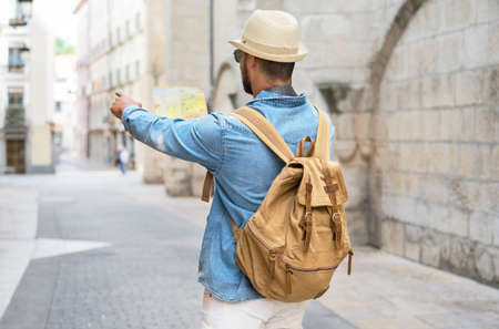 Handsome tourist man look at map while pointing finger in the direction of destination. Travel concept. Trip, backpacker tourist.の写真素材