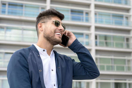 Handsome Man talking on cellphone outside modern office building.