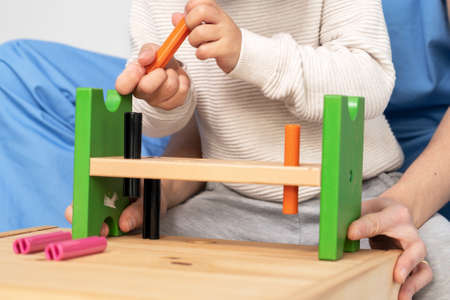 Close up view of a Therapist doing development activities with a little boy. Boy with cerebral palsy having rehabilitation, learning. Training in medical care centerの写真素材