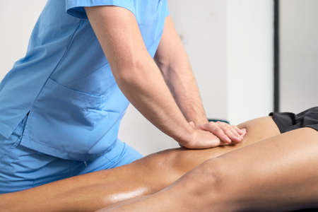 Close-up of therapist massaging young mans legの写真素材