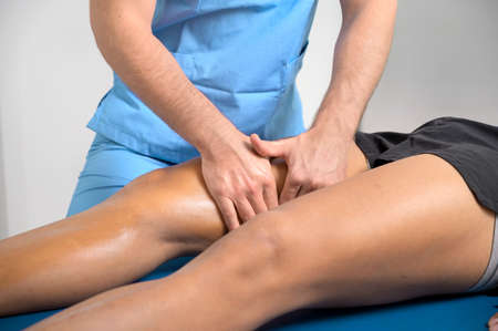 Close-up of therapist massaging young mans legの写真素材