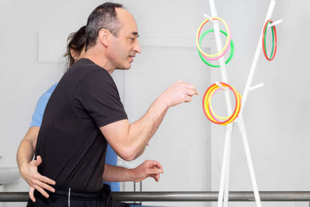 Physical therapist helping to disabled male patient, supporting during exercise therapy.の写真素材
