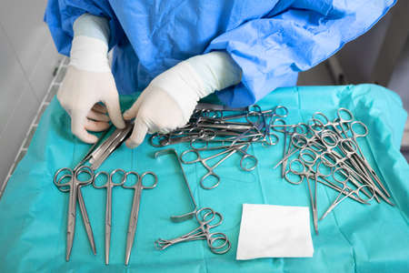Multiple surgery instruments on blue table above view. surgeon take surgical tools from table.