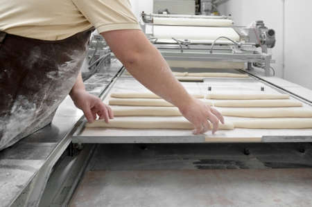 Baker working at industrial bakery preparing trays with fresh loaf.の写真素材