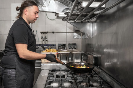Side view of male chef working in commercial kitchenの写真素材