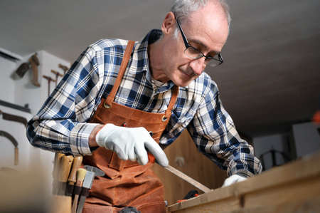 Carpenter filing a plank of wood in his Workshop.の写真素材