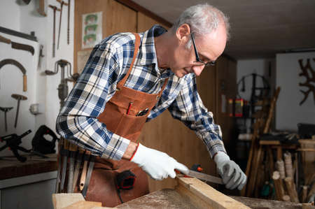 Carpenter filing a plank of wood in his Workshop.の写真素材